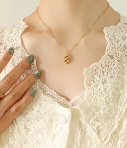 Close-up of gold-plated choker with geometric bead pendant worn by a model in lace