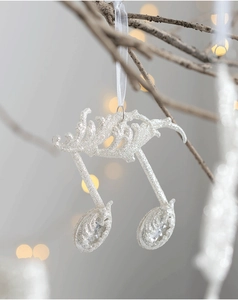 Macro shot of silver glitter music note ornament with white ribbon on holiday background