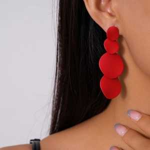 Macro side view of long red matte geometric earrings with four tiered irregular circles