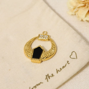 Macro shot of gold-plated geometric pendant with black stone and white cubic zirconia