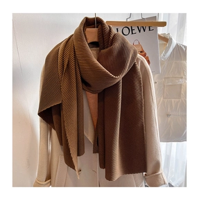 Close-up of deep coffee pleated scarf with thick wrinkled texture on a beige coat