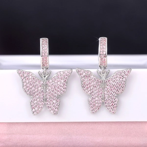 Macro shot of silver butterfly hoop earrings featuring sparkling pink zircon stones