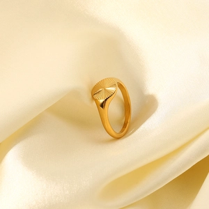 Détail d'une bague plaquée or 18K avec texture radiale sur fond de soie beige
