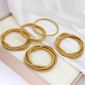 Elegant multi-layered gold stainless steel serpent coil bracelets on white silk