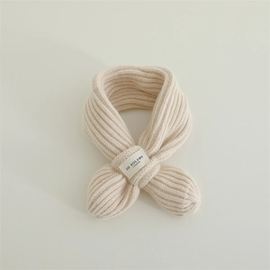 Detail view of cream beige chunky rib knit scarf with a woven brand label for children