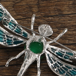 Macro view of the dragonfly brooch back showing silver metal texture and pin fastener
