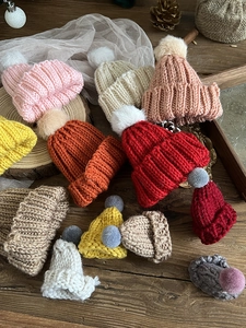 Mini colorful knitted Christmas hats with plush pom-poms on a rustic wood background