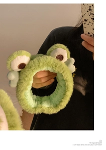 Dettaglio ravvicinato di una fascia per capelli a rana in peluche verde dalla texture morbida