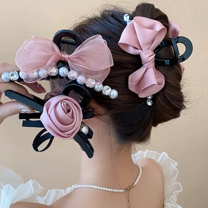 Detail of elegant pink bow and pearl hair claw clips on a model for a romantic hair style