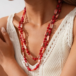 Détail du collier bohème à double rangée avec perles rouges et texture de coquillage
