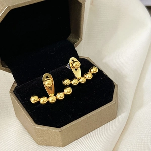 Detail of gold beaded earrings in a hexagonal gift box on luxury satin fabric