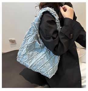 Close-up of light blue denim tote bag with diamond stitching and frayed fringe edges
