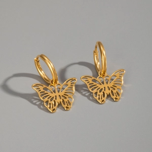Detailed macro view of golden cutout butterfly hoop earrings on a clean gray background