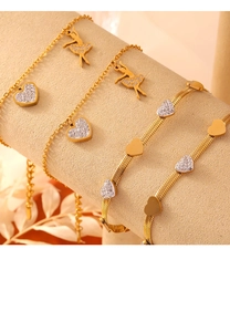Detailed macro view of gold-plated bracelets featuring heart charms and zircon stones
