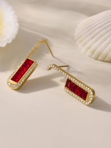 Macro view of gold U-shaped earrings with red zircon stones and pavé set white crystals