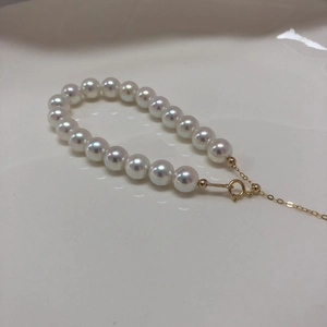 Macro detail of high-luster Aurora pearls and adjustable 14k gold-plated spring clasp