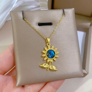 Vue détaillée du pendentif tournesol avec gemme étoilée bleue sur collier doré