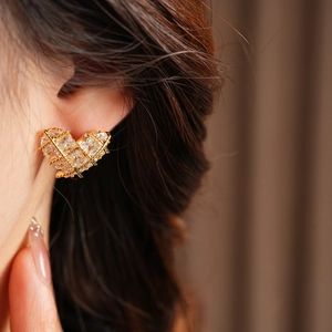 Gros plan d'un mannequin portant des boucles d'oreilles cœur dorées 18k avec zircons brillants