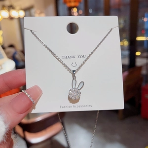 Detail of spinning rabbit pendant with zircon stones and white enamel on silver chain