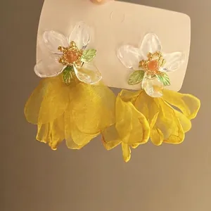 Detailed view of layered yellow organza flower earrings with white resin floral studs