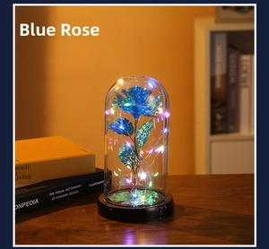 Detail of blue preserved rose in glass dome with LED fairy lights on a wooden table