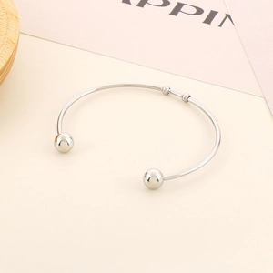 Detailed close-up of polished silver stainless steel open bangle with sphere ends