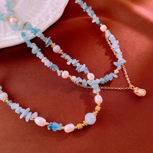 Aquamarine and pearl splice necklace with golden pendant on red satin background