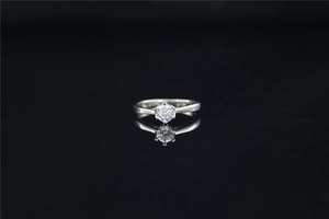 Detailed view of moissanite diamond ring with six-prong setting on black mirror background