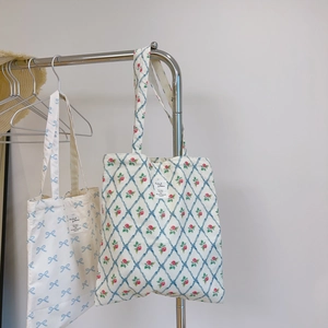 Detail of floral and bow pattern canvas tote bags hanging on a metal rack