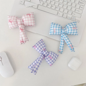 Detail of quilted silver cosmetic bags with colorful bows on a minimalist white desk