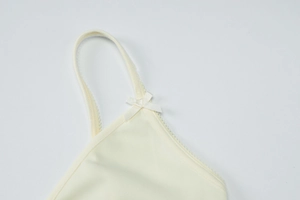 Gros plan sur la bretelle en tricot côtelé avec petit nœud sur le haut d'été jaune