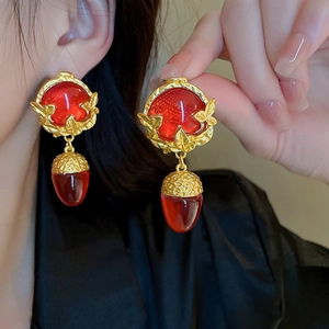 Close-up of vintage gold earrings with red drop gemstones worn by a female model