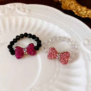 Handmade beaded bow ring set with sparkling crystals in a white ceramic dish