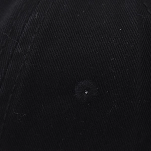 Détail macro du tissu en sergé de coton noir et de l'œillet brodé sur la casquette