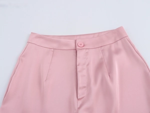 Détail du pantalon en satin rose montrant la taille, le bouton assorti et la braguette