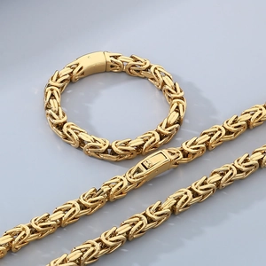 Golden Byzantine chain necklace and bracelet set in hip hop style on grey background