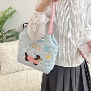 Detail of light blue quilted tote bag with cute dog embroidery and pink handles