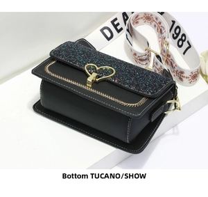 Detailed side view of black crossbody bag with blue glitter and gold heart clasp