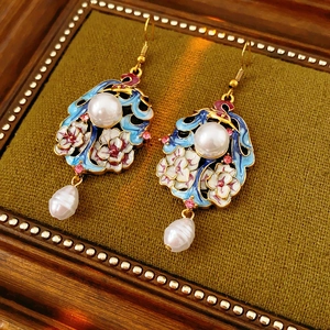 Detail of vintage enamel floral earrings with large pearls on green velvet