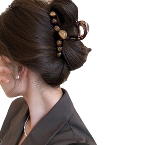 Grande molletta per capelli marrone con perle ambrate vista laterale sui capelli