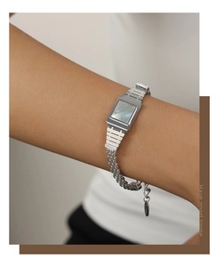 Détail d'un bracelet chaîne argenté avec incrustation carrée de nacre porté au poignet