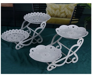 Detail of white metal tiered cake stand with ornate镂空 patterns and butterfly designs