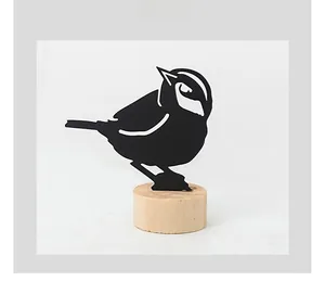 Close-up of minimalist black metal bird silhouette with a natural wooden base ornament