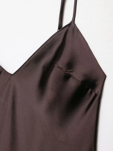 Gros plan du décolleté de la robe en satin marron foncé et des fines bretelles élégantes