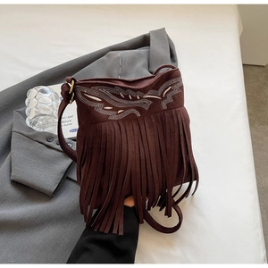 Detail of dark brown suede shoulder bag featuring ethnic embroidery and long fringe trim
