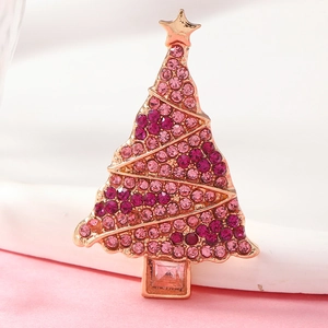 Close-up of a rose gold Christmas tree brooch with pink rhinestones and a gold star top