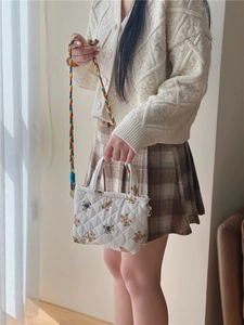 Close-up of quilted floral crossbody bag with cute bear print and colorful braided strap