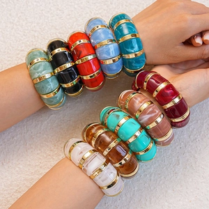 Close-up of colorful acrylic bamboo-style bangles with gold spacers on wrists