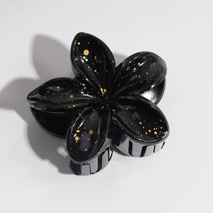 Detail of black lily hair claw clip with glossy finish and gold glitter accents