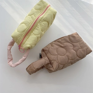 Detailed macro of floral quilted cosmetic bags in light yellow and brown polyester